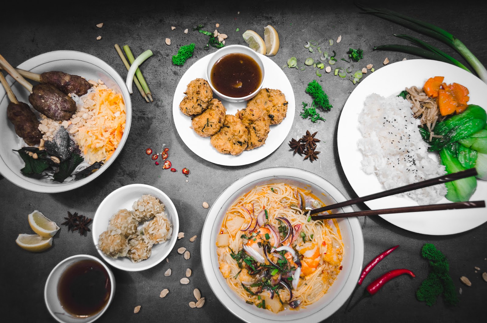 Bohatá hostina vietnamských specialit na tmavém pozadí.